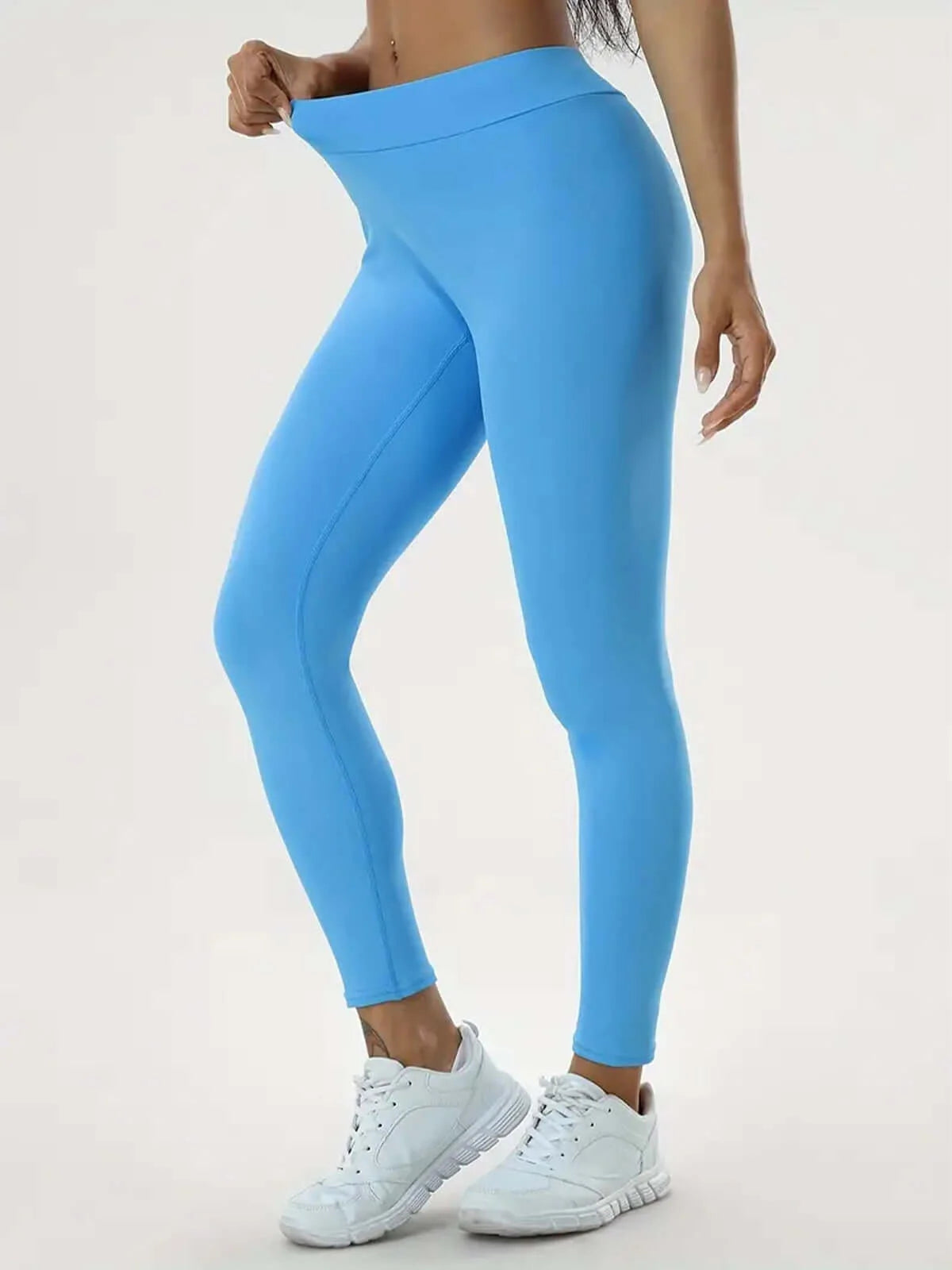 Woman wearing blue high-waist sculpting leggings and white sneakers, showcasing a sleek, sculpted silhouette for fitness activities.