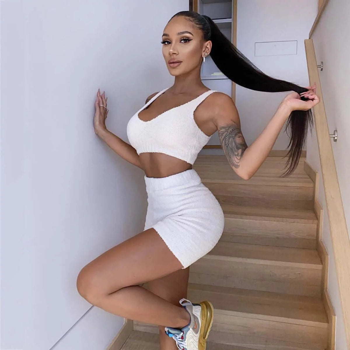 Model wearing white knit tank top and shorts on staircase
