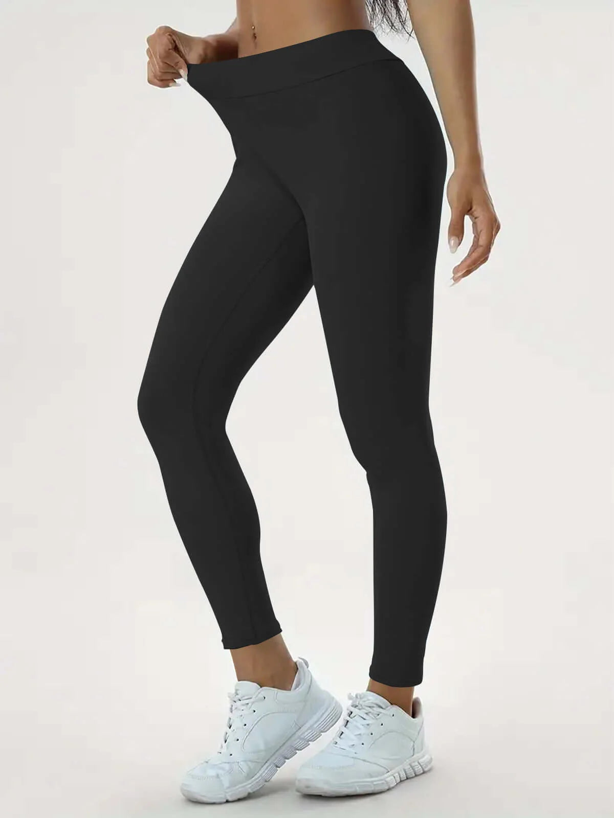 Woman wearing high-waist sculpting leggings in black with white sneakers, showcasing stretch and fit.