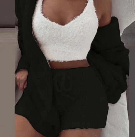 Woman wearing women's 3 piece lounge pajama set with top, shorts, and cardigan in cozy indoor setting.